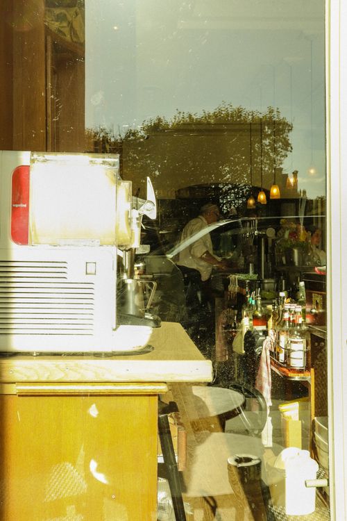 Free View through a window into a bustling cafe in Paris, capturing daily hustle with coffee machines and patrons. Stock Photo