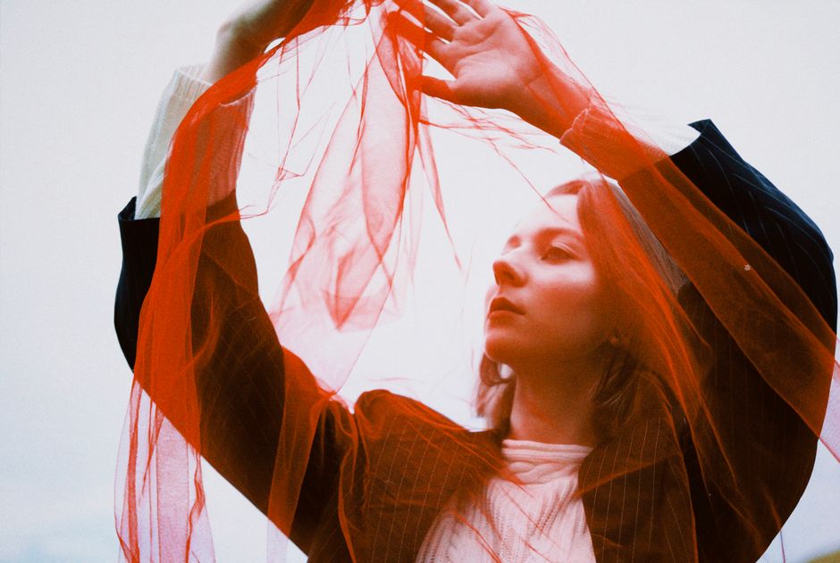 A creative portrait of a woman with a red scarf, blending fashion and art in an outdoor setting.