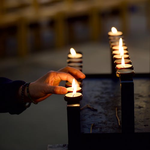 A person holding lit candles in front of a black table
