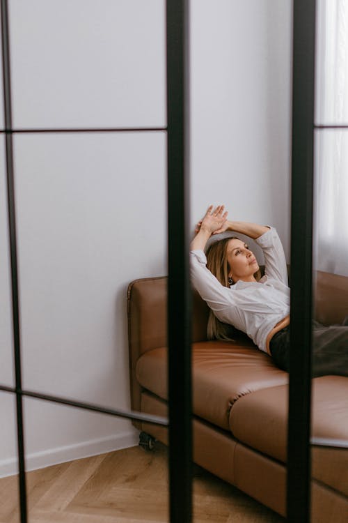 Woman Lying Down with Hands Raised on Sofa