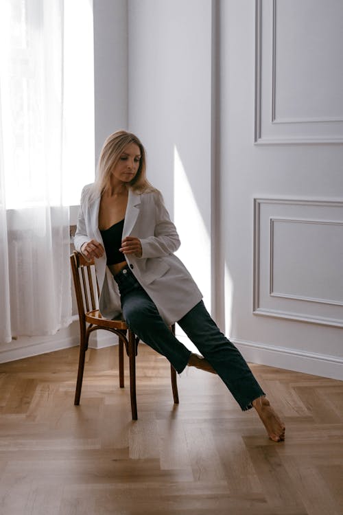 Blonde Model in White Jacket Sitting on Chair