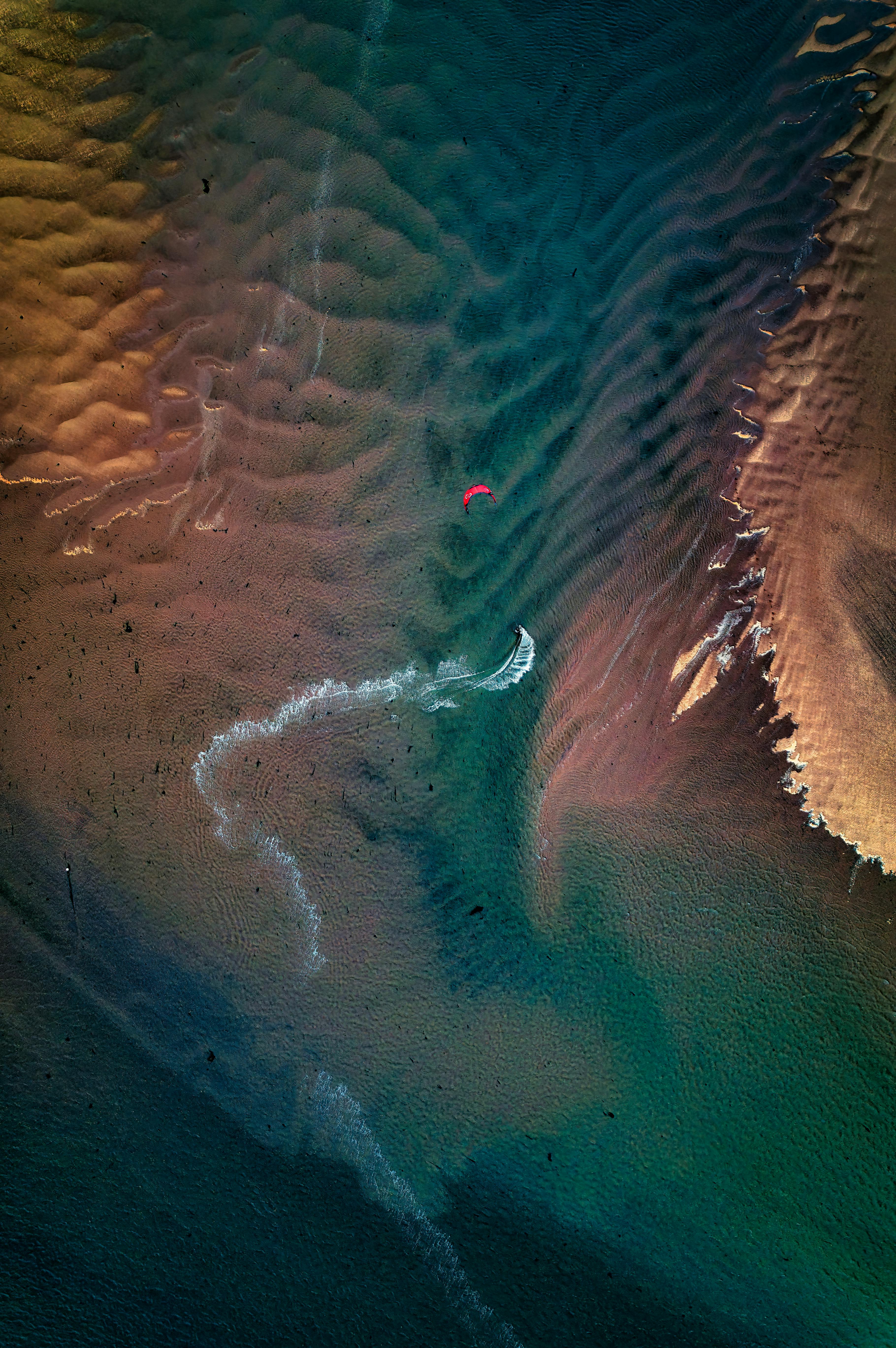 Scenic aerial shot capturing a lone kite surfer on the shores of Exmouth, UK.
