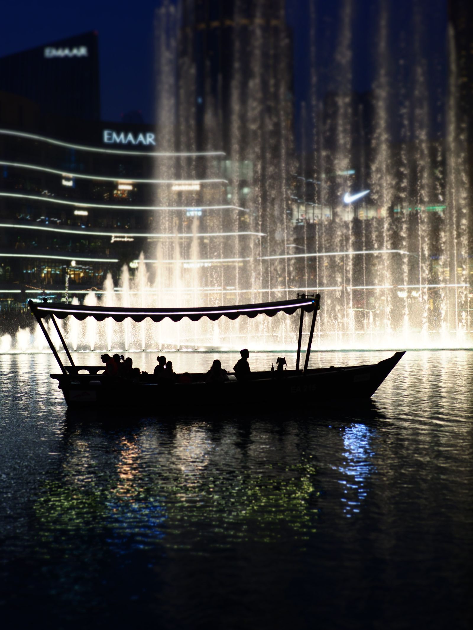 Passengers in a traditional abra on Burj Lake during the Dubai Fountain show at night