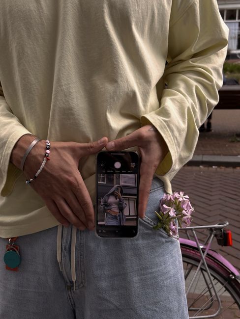 Man in casual attire taking a photo with a smartphone, showcasing urban street fashion.