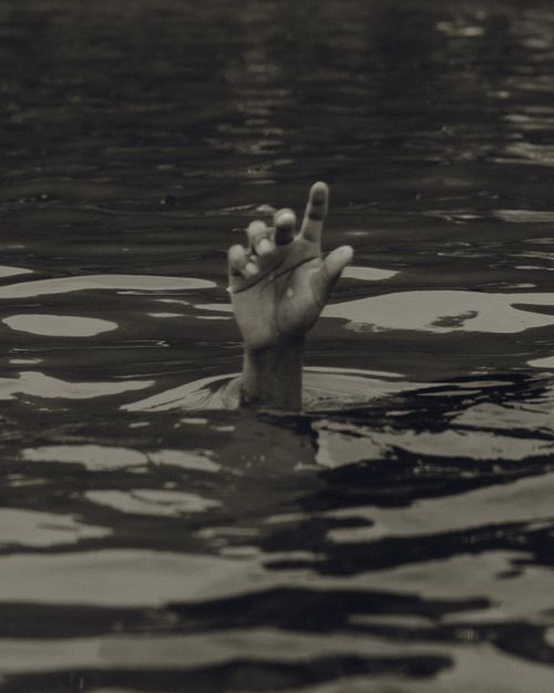 Free A hand reaching from beneath water surface, evoking themes of struggle and hope. Stock Photo