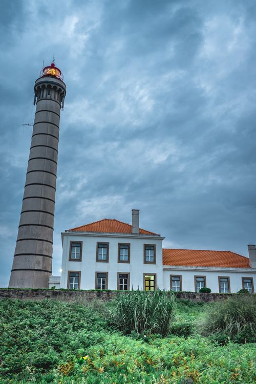 Free Explore Porto's vibrant architecture and unique lighthouse surrounded by lush greenery and dramatic skies. Stock Photo