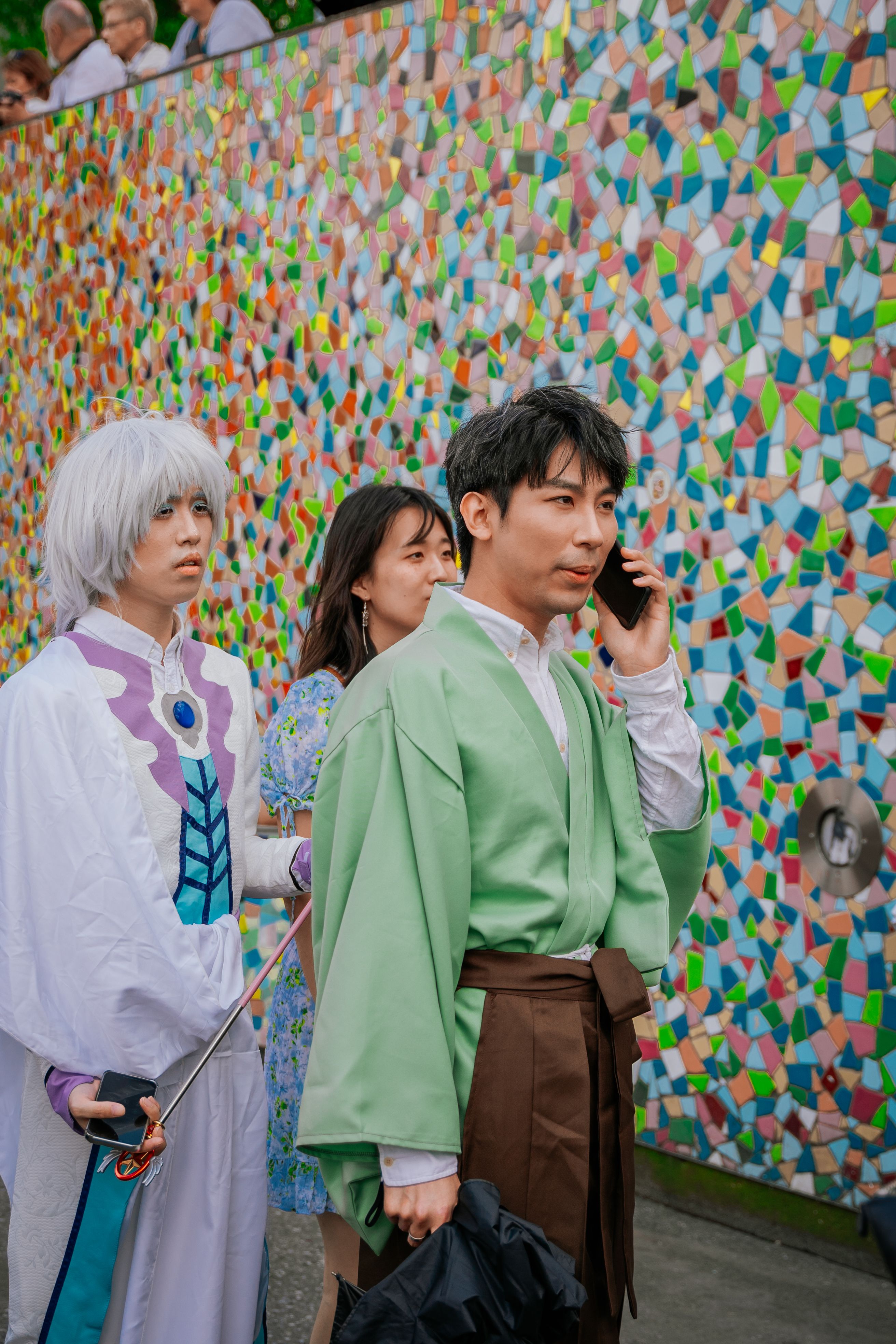 Vibrant cosplay scene with diverse characters in Düsseldorf, Germany, showcasing colorful styles against a mosaic background.