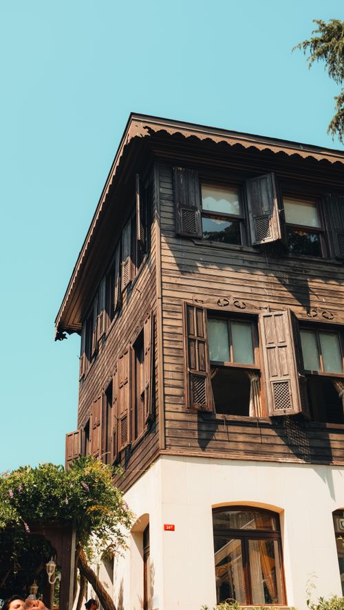 Free A picturesque wooden house with open shutters in a sunlit Turkish town. Ideal for travel and architecture imagery. Stock Photo