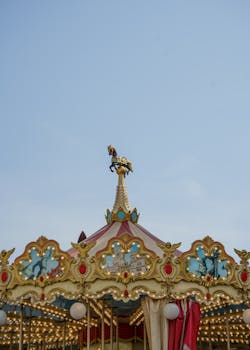 A beautifully decorated carousel top at an amusement park in Valencia, Spain, against a clear sky.
