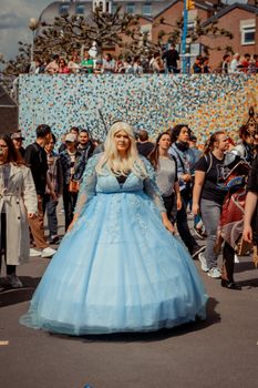 A vibrant street festival in Düsseldorf with people in costumes and a woman in a blue dress.