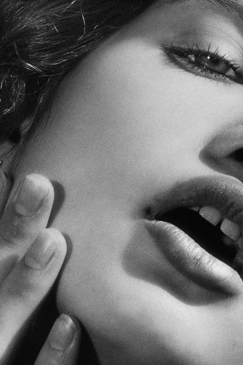 Free Artistic black and white close-up of a woman's face with an expressive open mouth and gentle fingers. Stock Photo