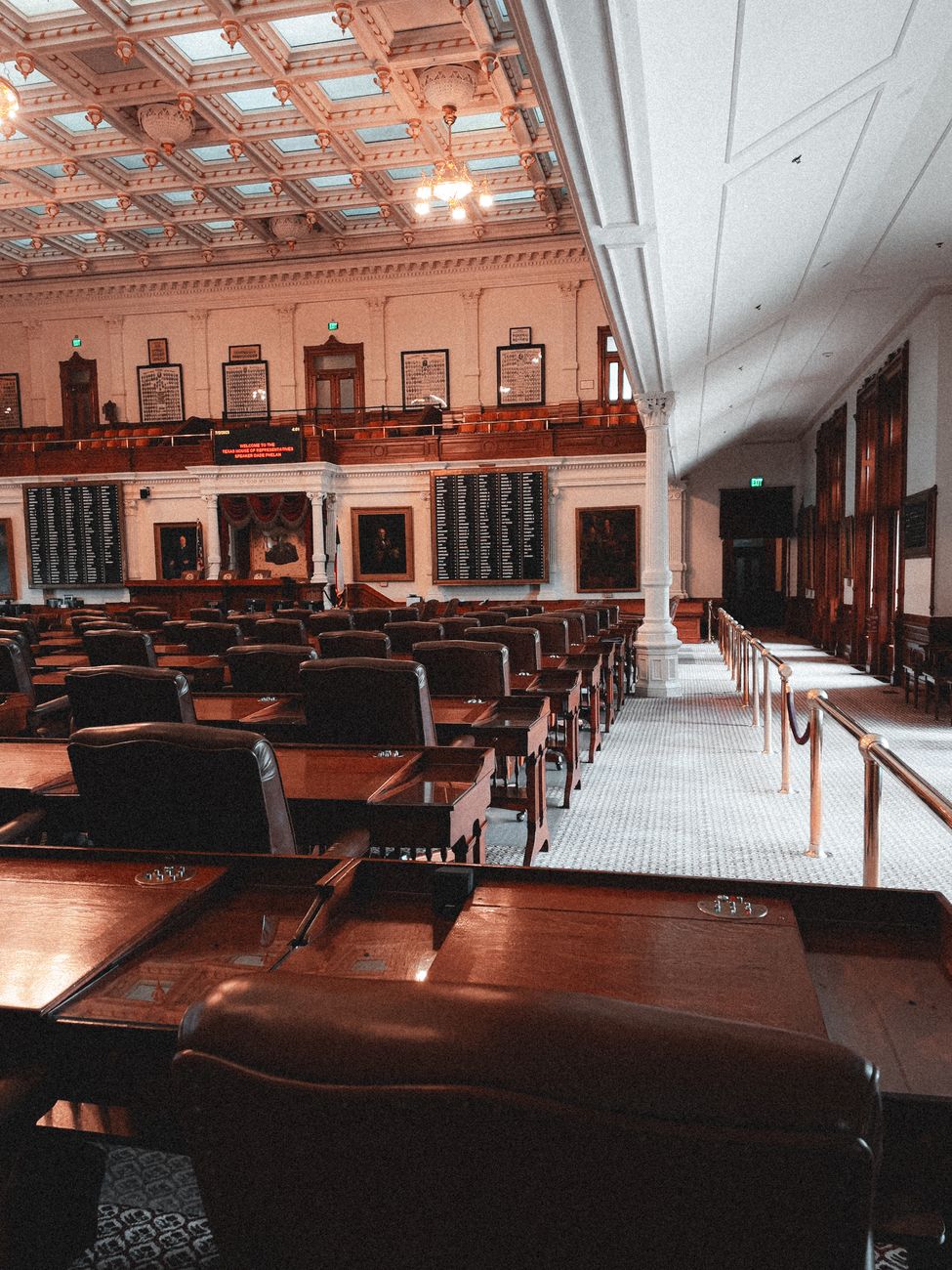 Interior of a British town hall council chamber with wooden benches and tall windows