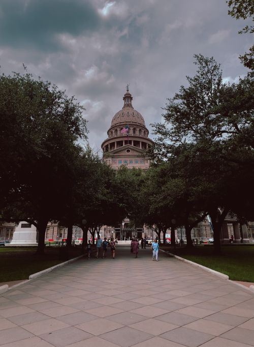 Free View of the Texas Capitol with its distinctive dome through a tree-lined path. Stock Photo