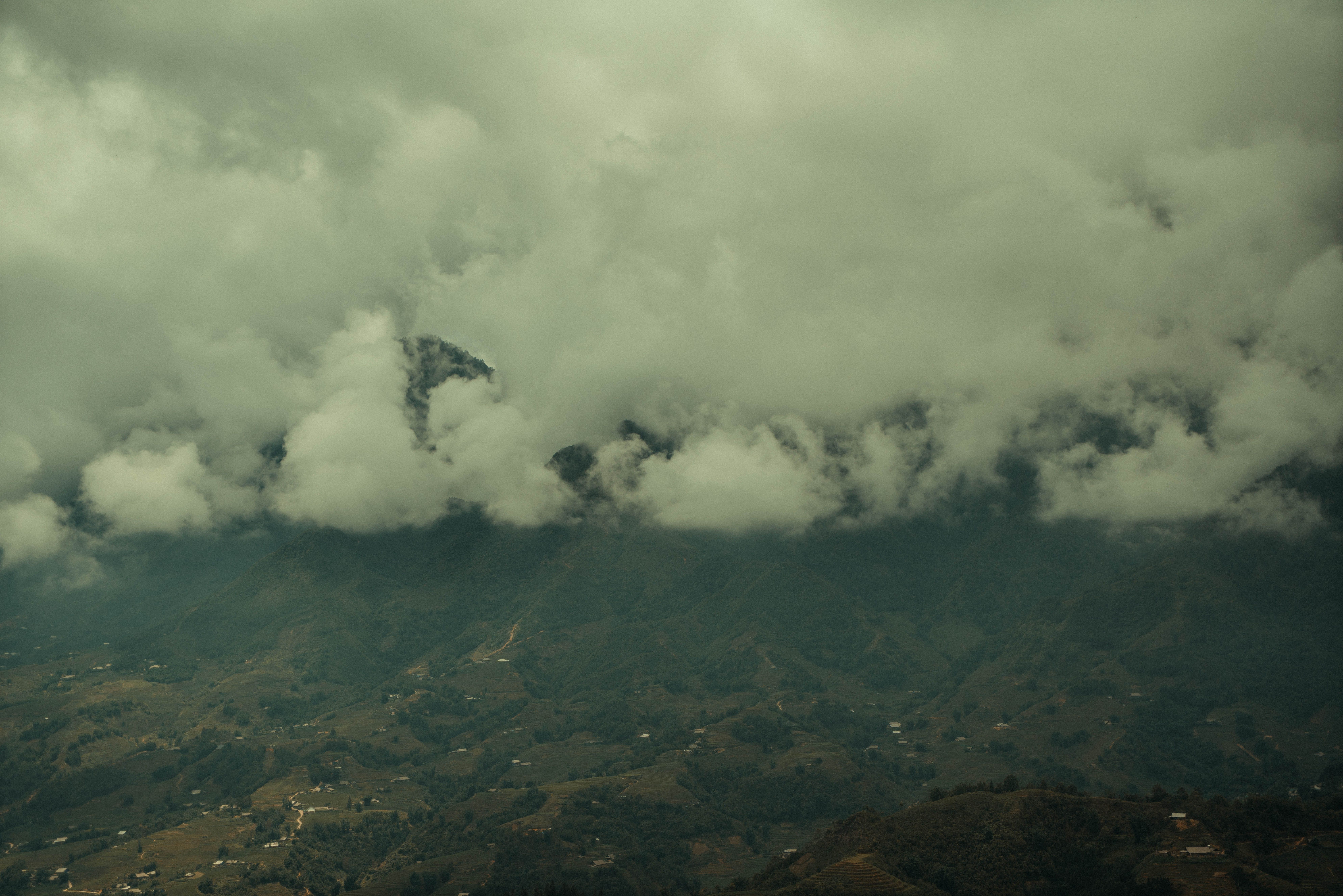 An aerial view of a mountain valley shrouded in dense clouds, creating a dramatic landscape scene.