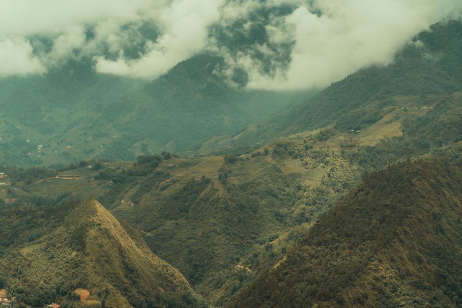 Aerial view of lush green mountains and valleys covered in clouds.