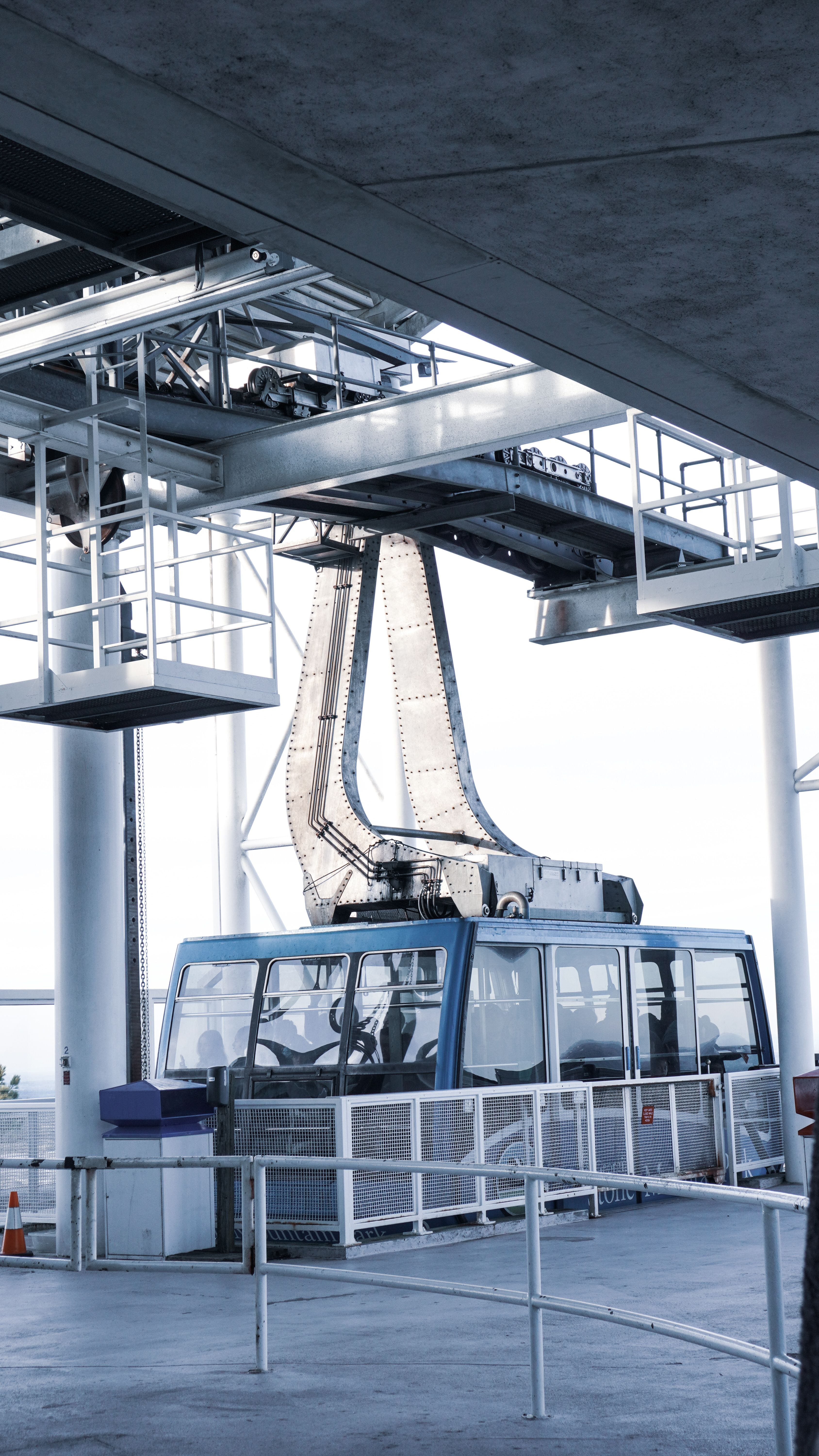 A modern funicular cabin located in a sleek urban station with steel railings and machinery.