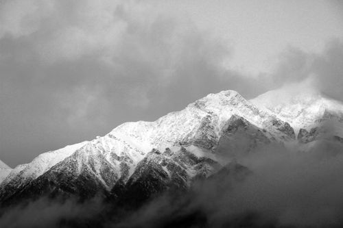 Free Stunning black and white shot of snow-capped mountain peaks under cloudy skies. Stock Photo