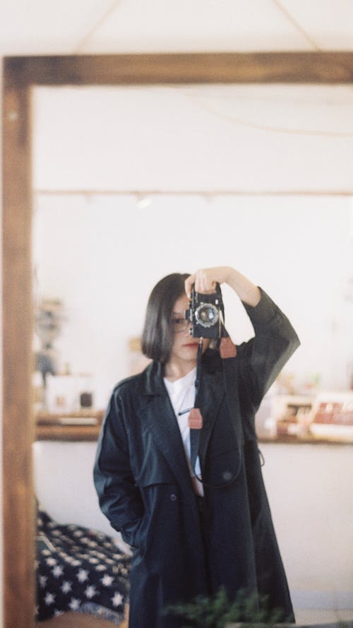 Young Woman Taking a Mirror Selfie with a Film Camera 