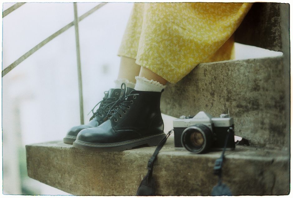 Retro style with black boots and vintage camera on concrete steps, evoking nostalgia.