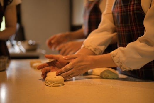 Close-up of hands shaping dough in a warm kitchen setting, perfect for baking enthusiasts.