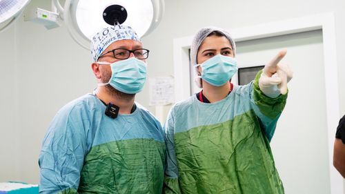 Free Two surgeons in masks and gowns discussing a procedure in a hospital operating room. Stock Photo