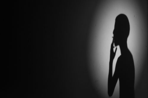 Free A silhouette of a person smoking against a dimly lit background, creating a mysterious effect. Stock Photo