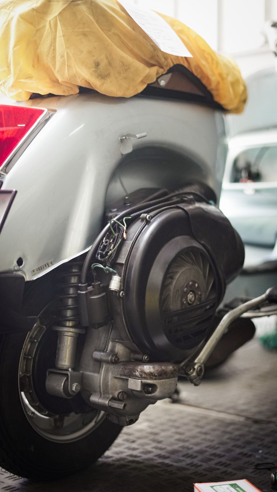 Detail roda belakang dan mesin skuter matic di dalam garasi