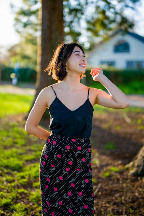 Standing Young Woman Smiling at Something Off Camera at Sunset in a Local Park