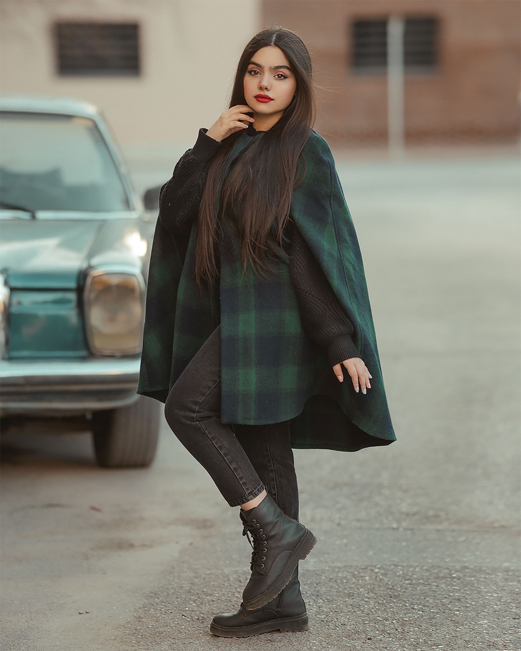 Curvy woman in green plaid poncho cape outfit styled with jeans and boots