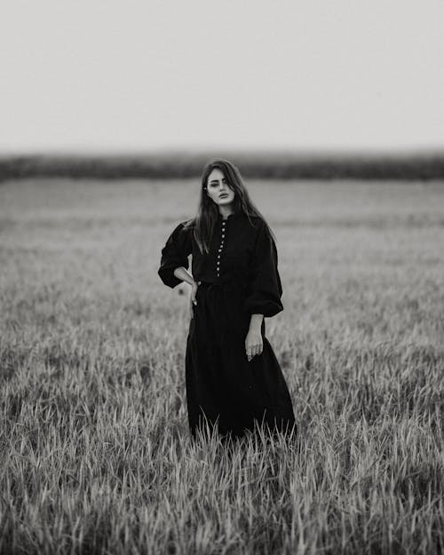 Black and White Photo of a Woman Standing in a Field 