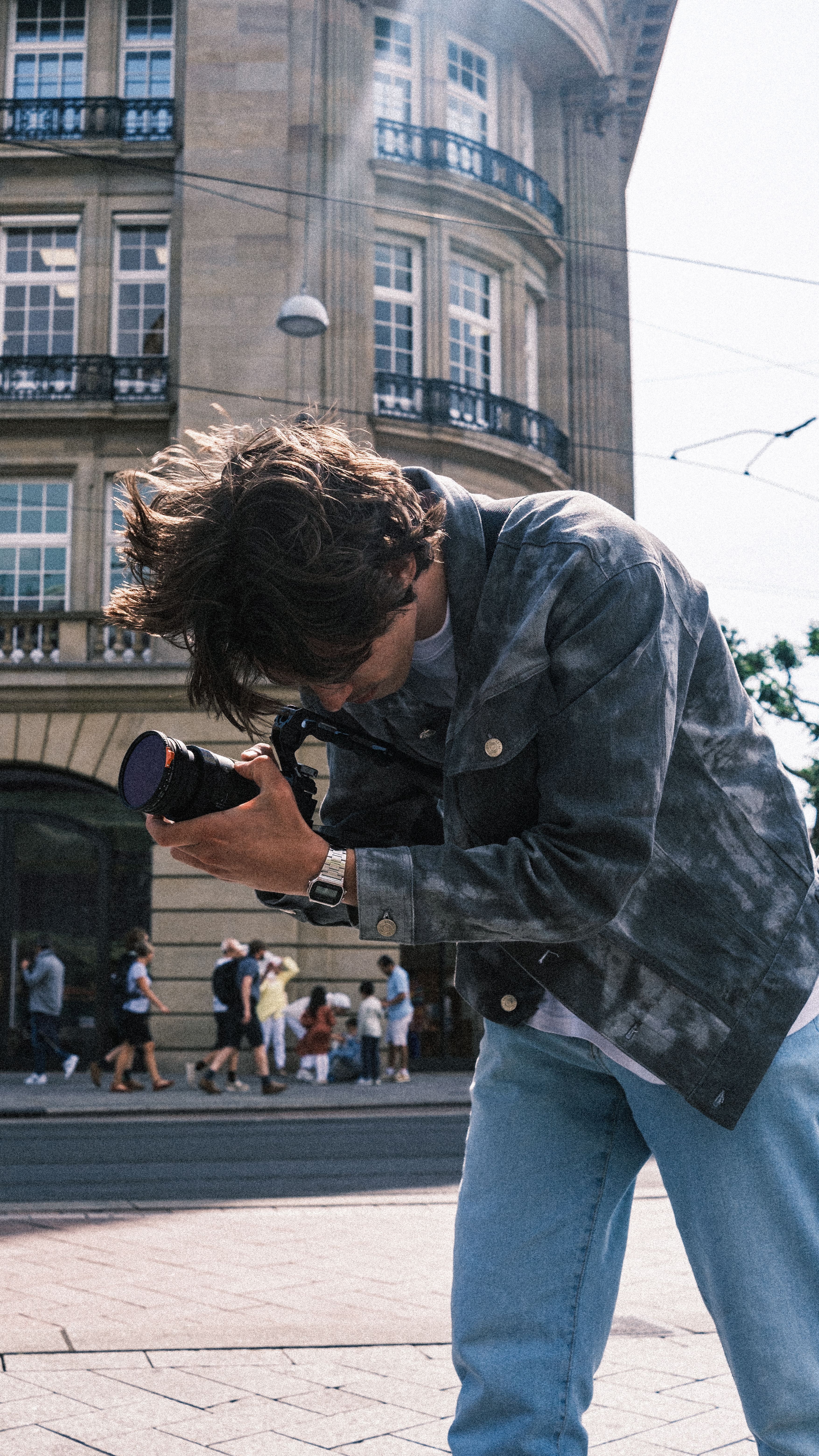 A young photographer in a city street capturing the essence of urban life.