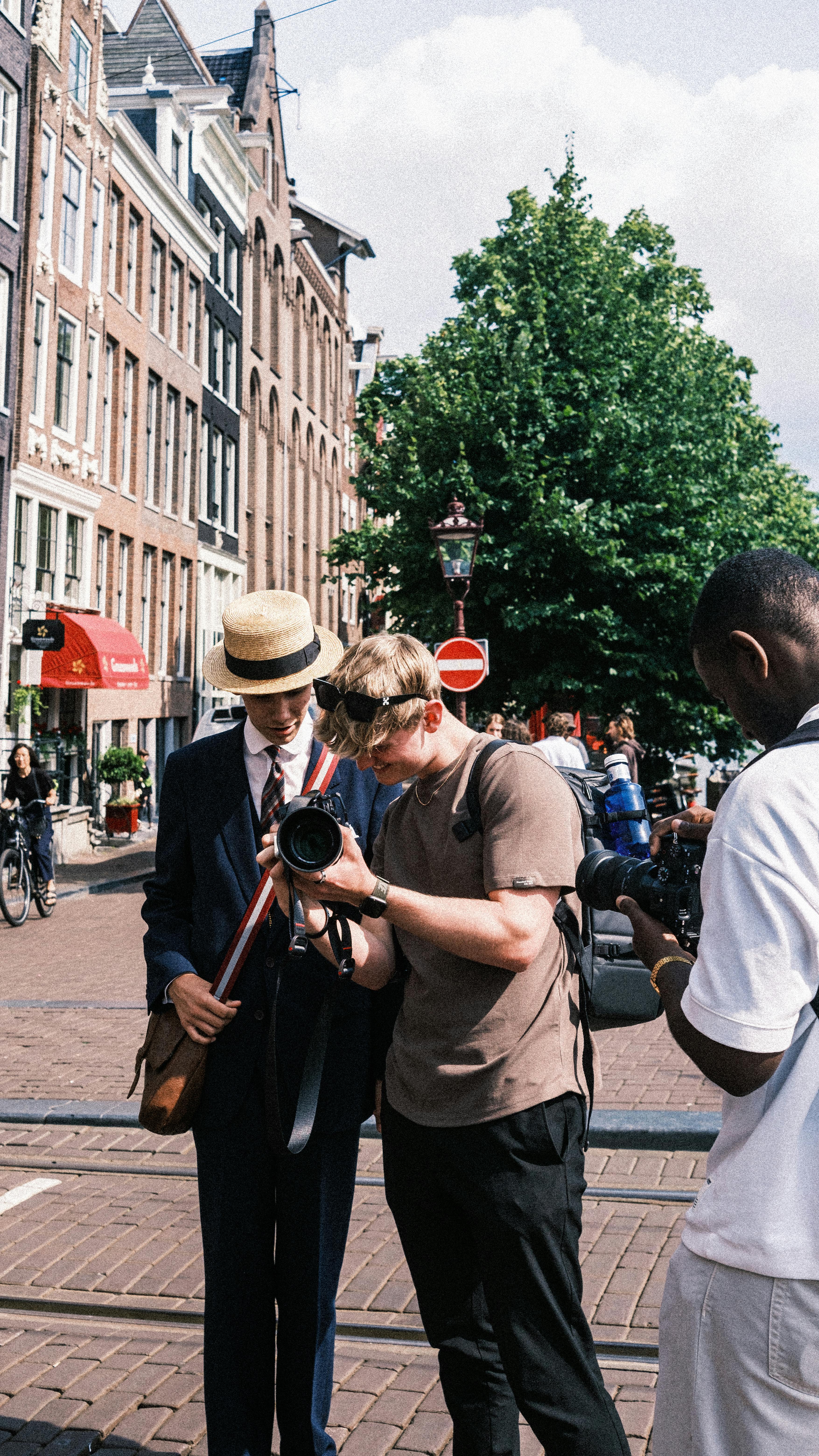 young men standing on a street looking at photos on a digital camera screen