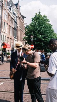 Three men engage in street photography on a sunny day in a European city.