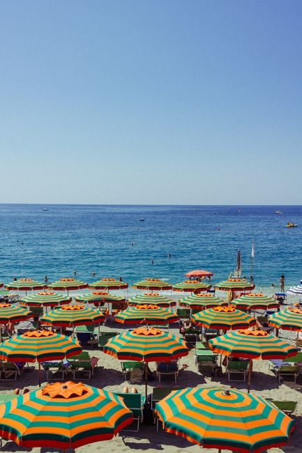 Colorful striped umbrellas on a sunny beach with a serene blue sea view.