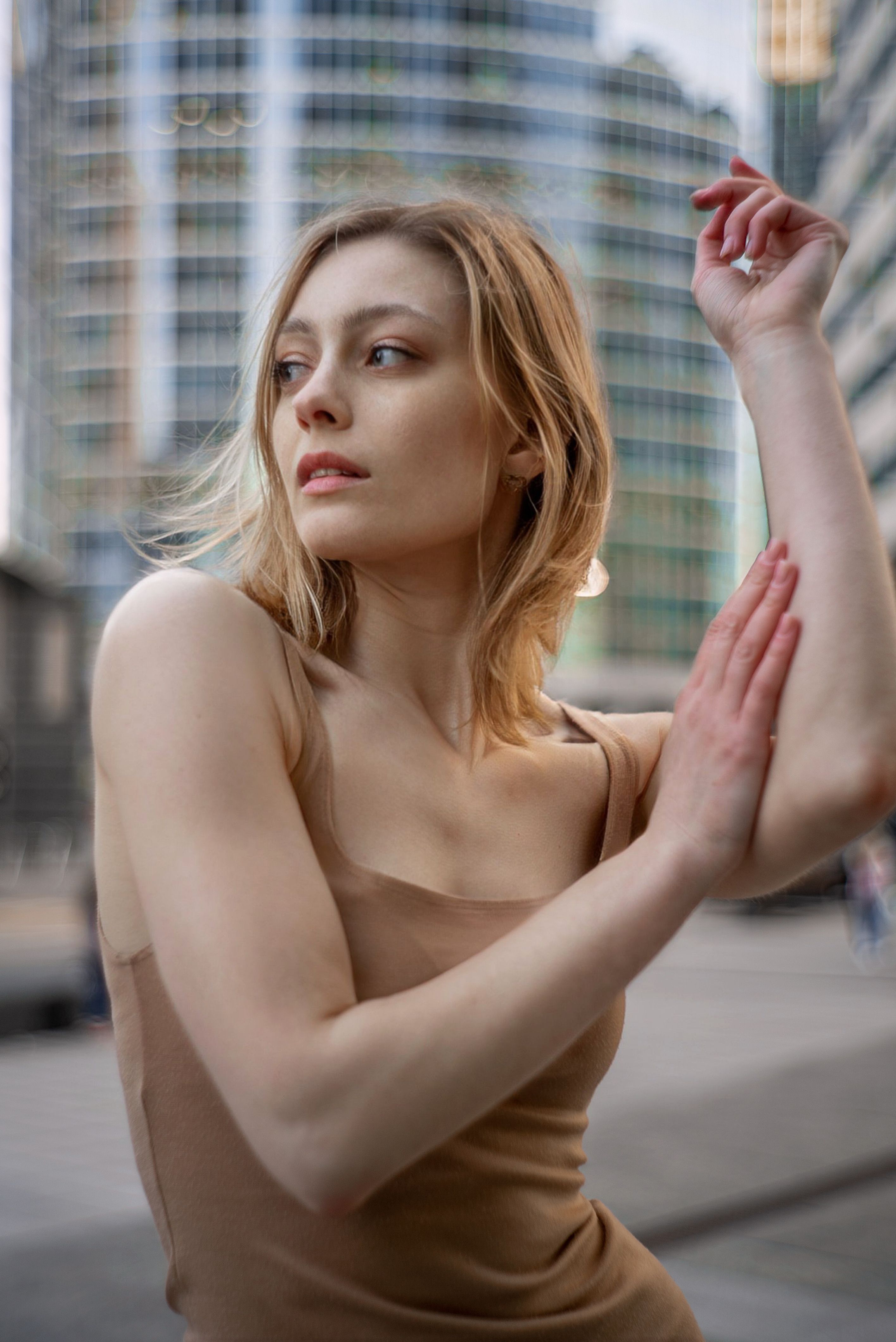 Elegant woman posing in a fashionable dress against a modern city backdrop.