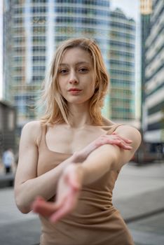 Blonde woman with long hair poses confidently in a modern urban environment.
