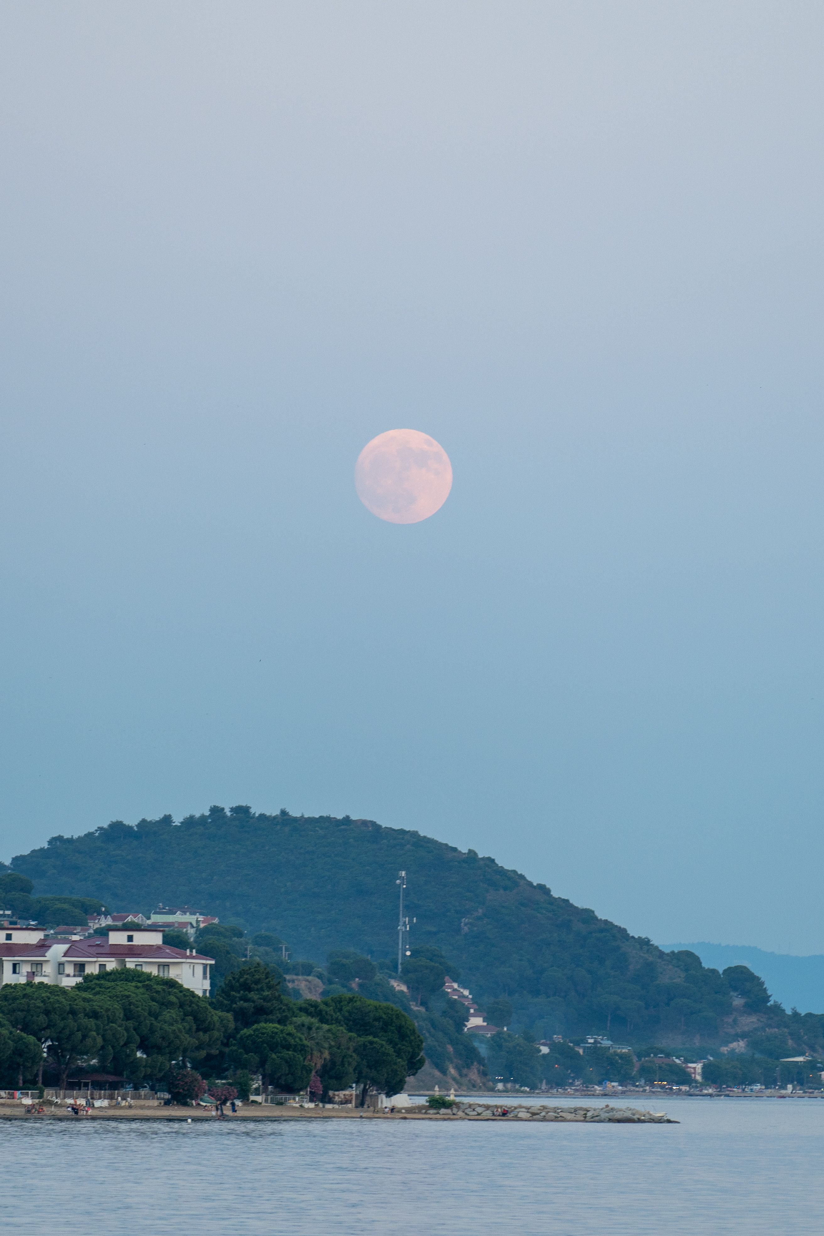 A full moon rising over a small town and water · Free Stock Photo