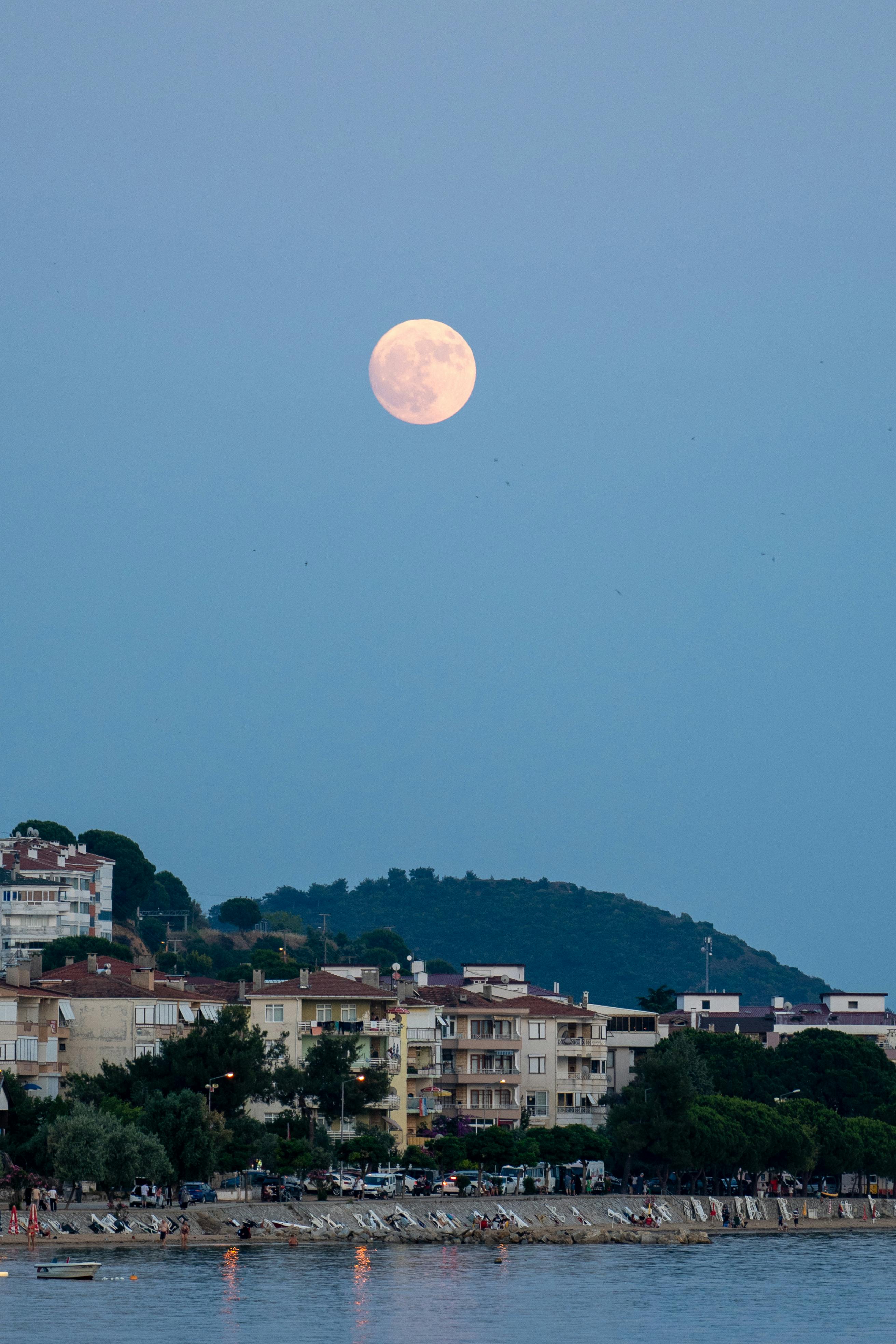 the full moon rises over the water and buildings