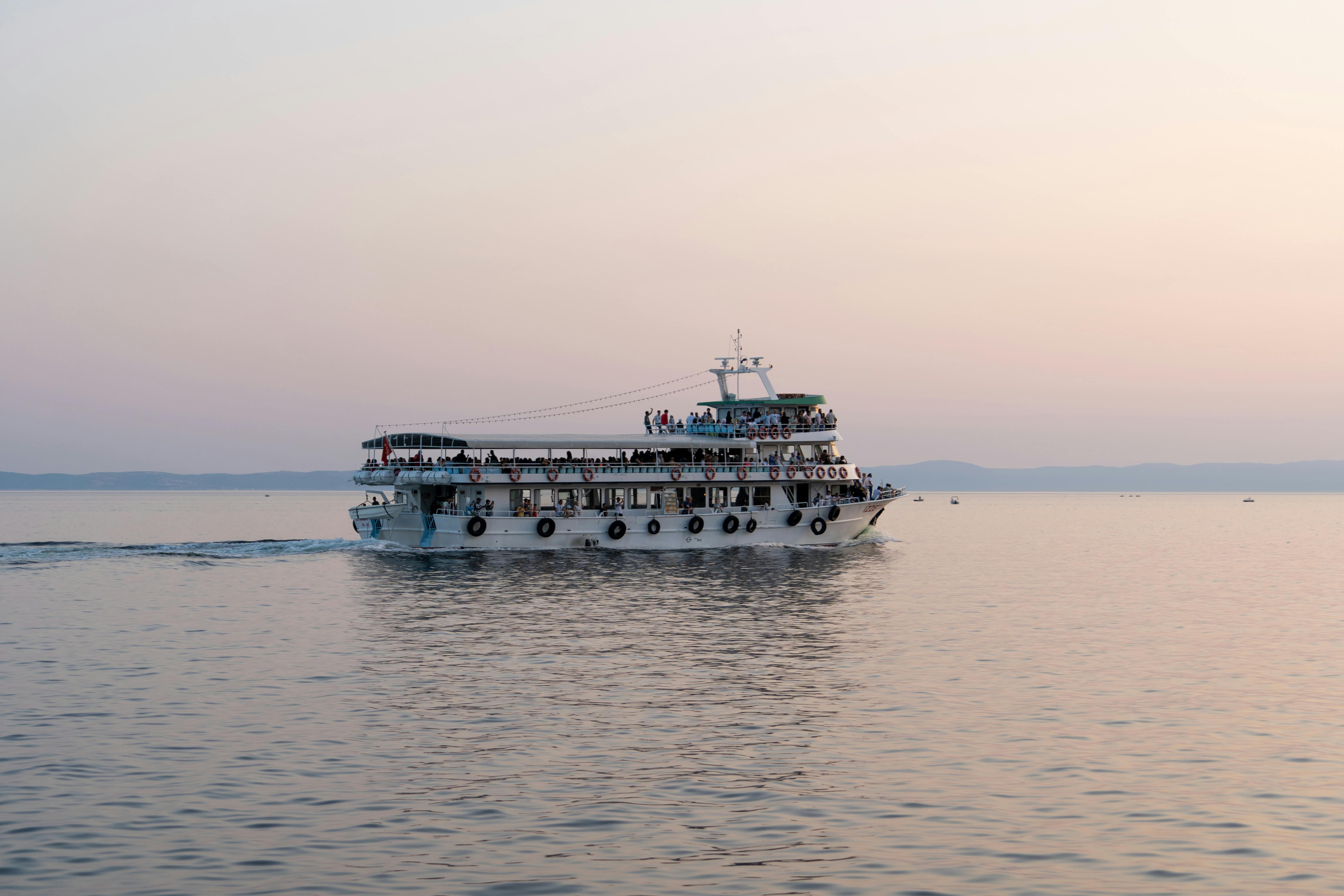 Free A serene image of a cruise ship sailing on calm waters during a beautiful sunset. Stock Photo