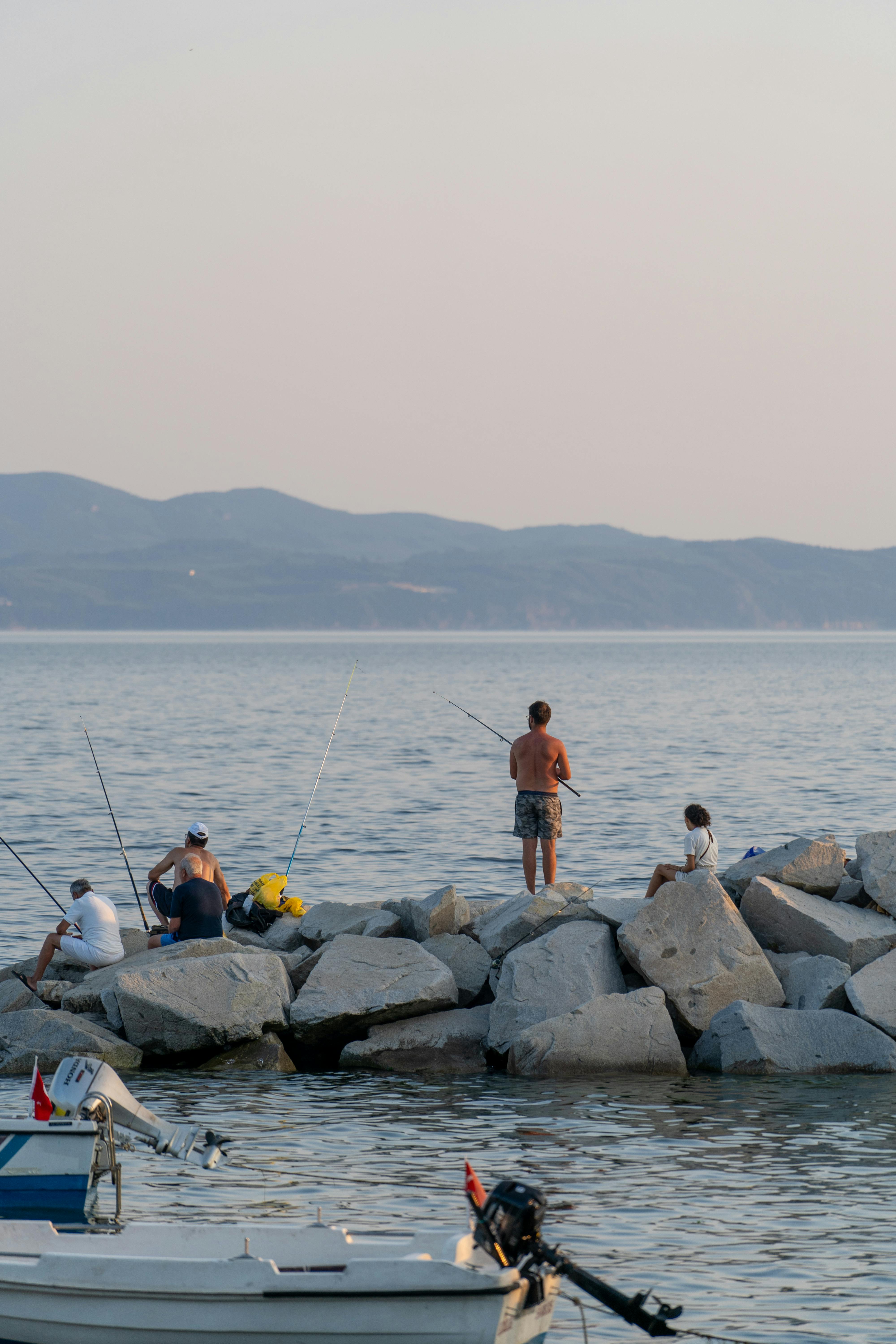A group of people fishing on the rocks · Free Stock Photo