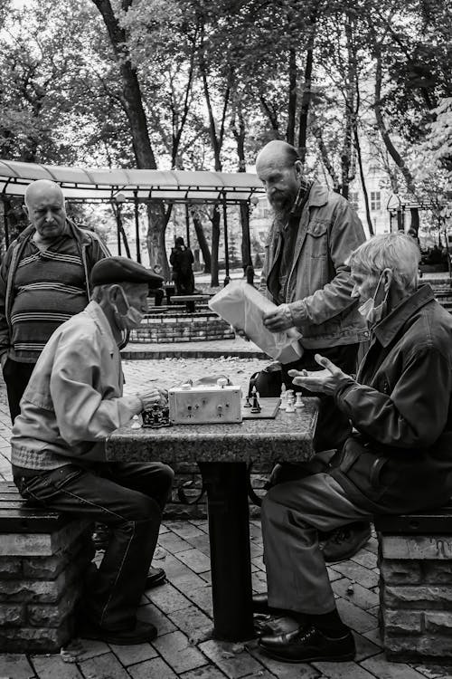 Men Playing Chess on Table in Park