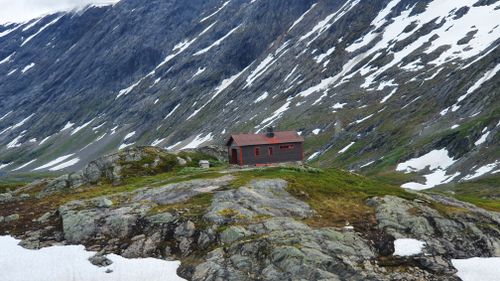 Free Solitary wooden chalet surrounded by snowy mountains and rocky terrain during winter. Stock Photo