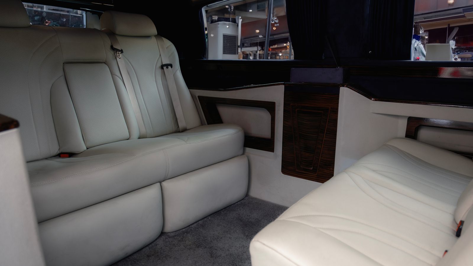 Illustrative luxury passenger-van interior with white leather seating and dark wood trim