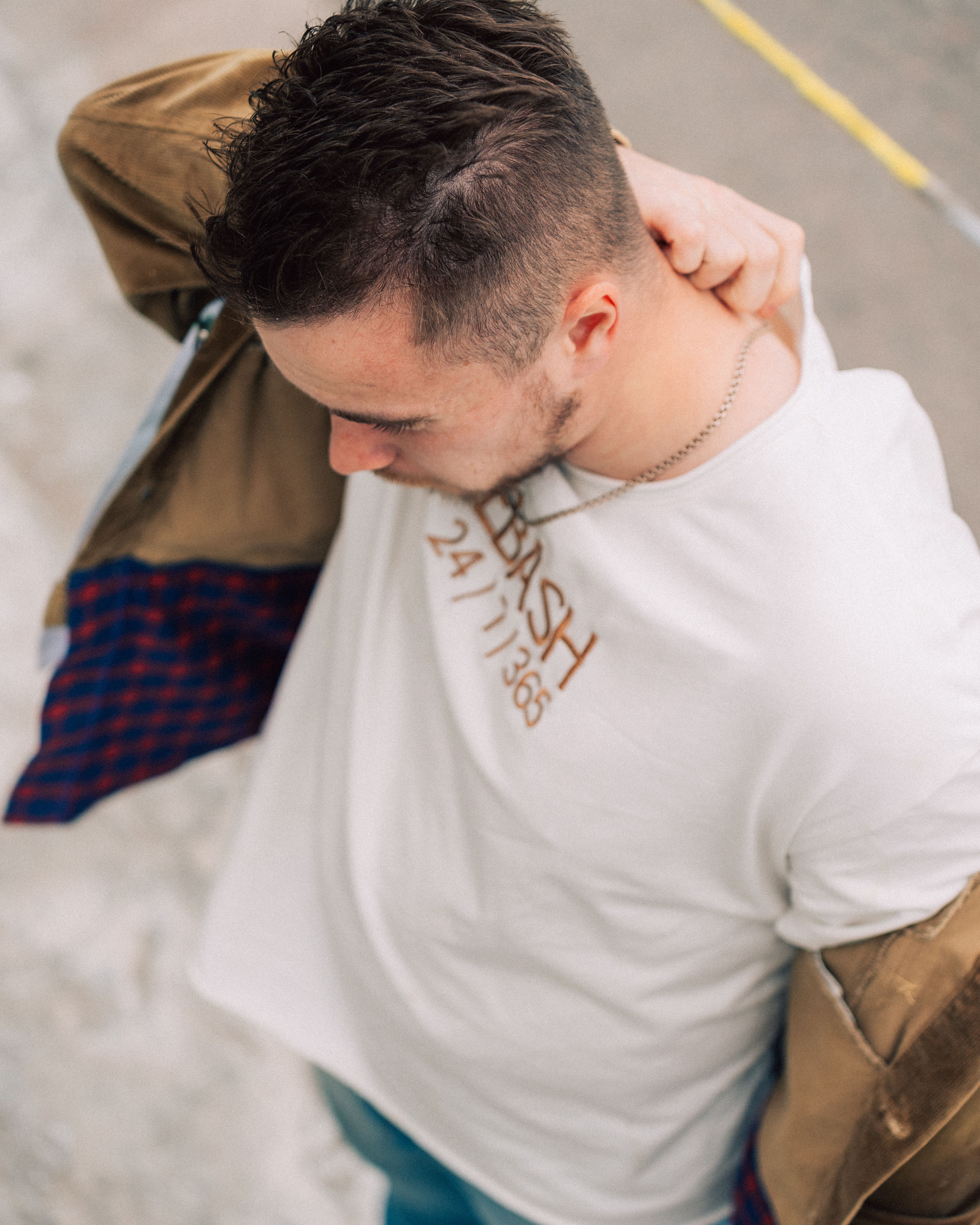Young man in casual fashion posing with a jacket in an urban environment.