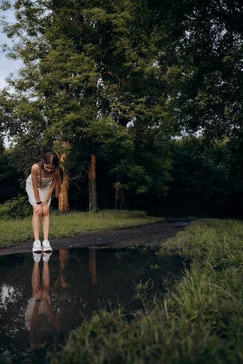 Woman Bending over Puddle