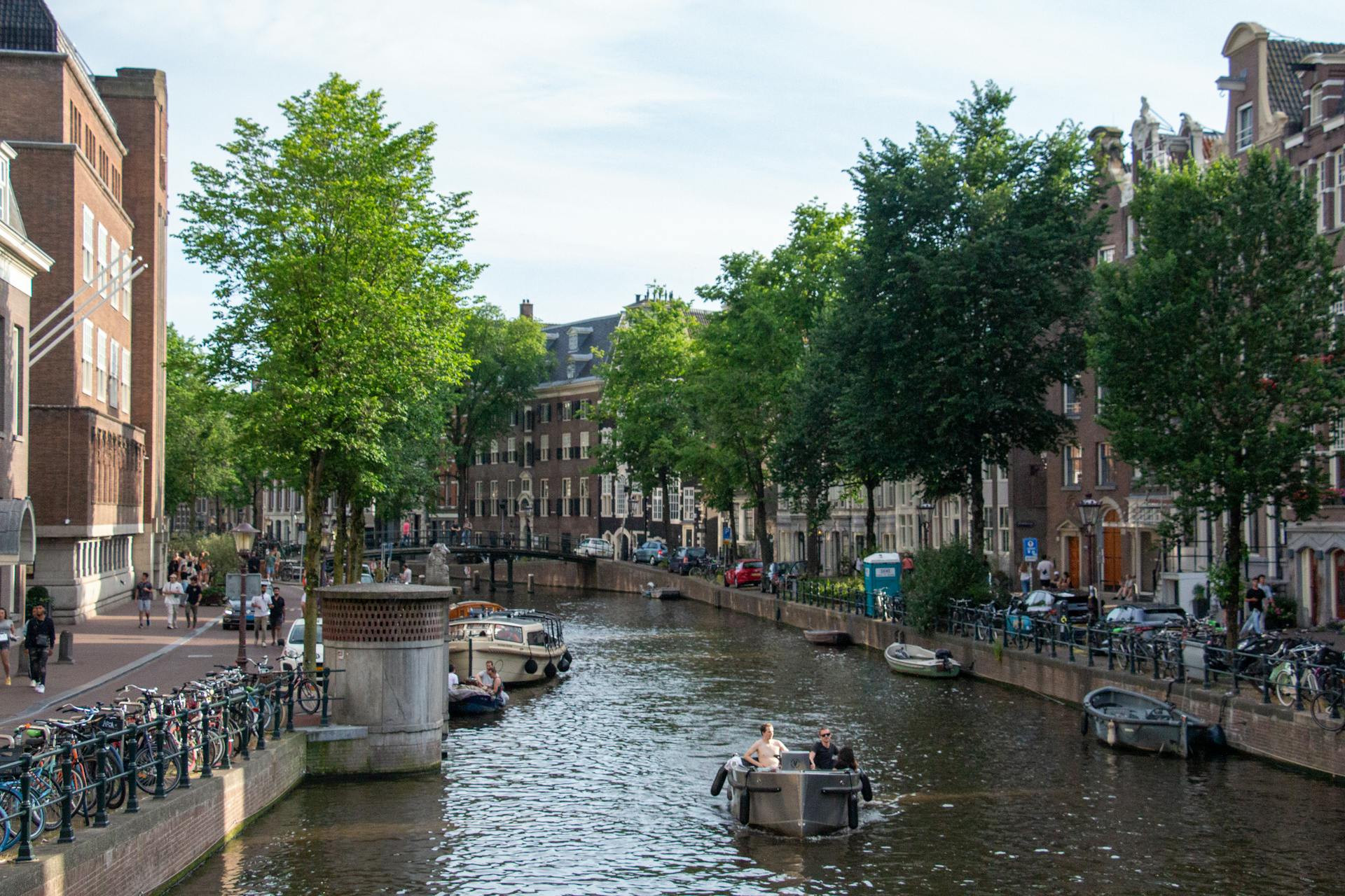 Explore the scenic Amsterdam canal with boats and historic buildings lining the water.