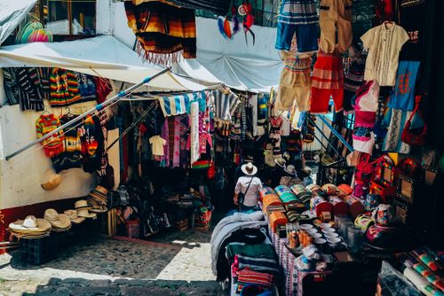 Free A bustling outdoor market stall showcasing traditional clothing and crafts in an inviting atmosphere. Stock Photo