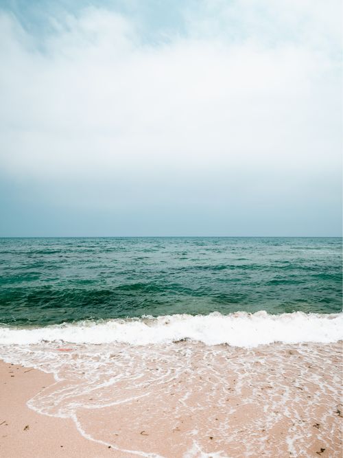 Free Peaceful ocean view with gentle waves lapping a sandy beach under a clear sky. Stock Photo