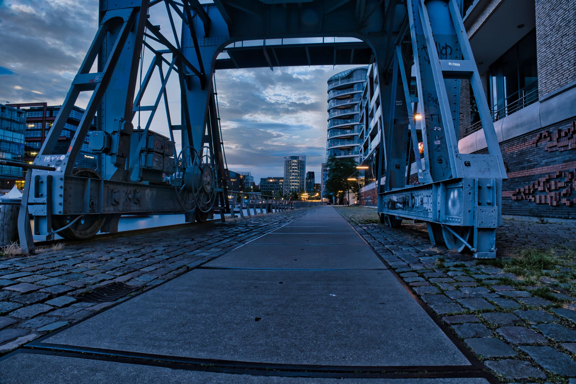 A scenic urban view featuring an industrial structure and modern buildings at dusk.