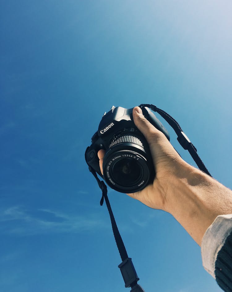 Photo Of Hand Holding Up A Black Canon Dslr Camera